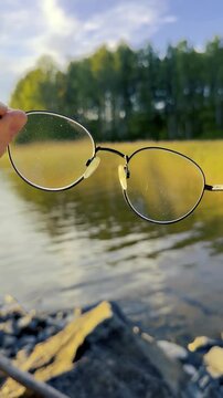Eyeglasses Held Against a Lake Sunset Vertical Video