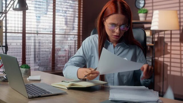 Irritated Caucasian business woman writing notes managing documents searching information looking in laptop feeling stress work trouble at office table businesswoman female girl multitask problem