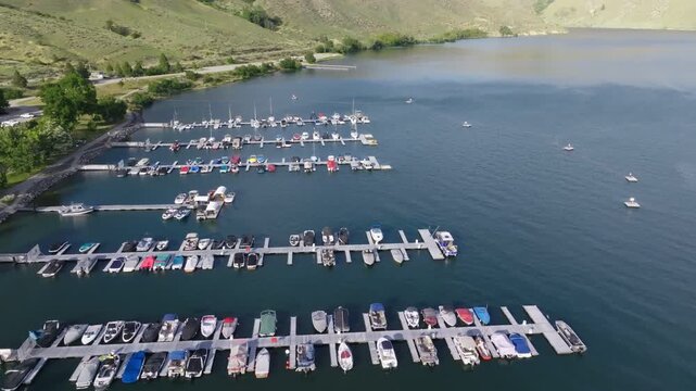 Aerial view of Lucky Peak Lake marina with numerous boats docked in slips on calm water surrounded by rolling hills in Ada County, Idaho, United States.