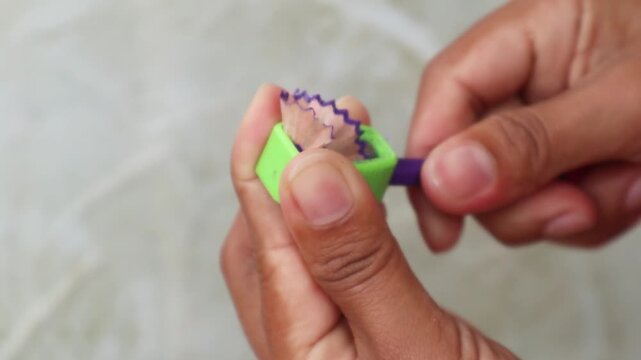Sharpening colored pencils with manual sharpener creating wood shavings and sharp tips in 4K Ultra HD footage.
