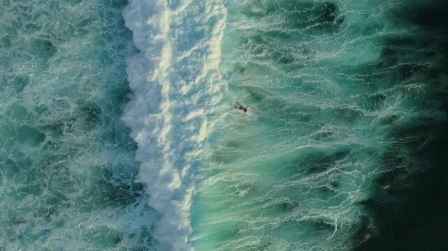 Cinematic aerial tracking of surfers in turquoise ocean water below Jaran Hill in Uluwatu Bali &ndash; Breathtaking bright daylight illuminating tropical sea surf lineup, commercial stock video 4k UHD asset