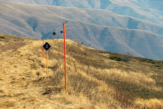 View of Stara planina mountain landscape with orange trail markers and numbered signs along a dry grassy path in Babin zub, Pirot District, Serbia.