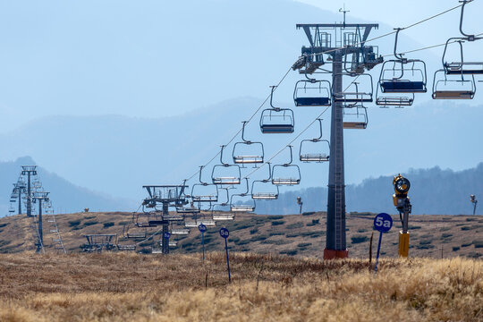 View of the Stara planina ski lift with empty chairs suspended on cables, snowmaking equipment, and rolling mountain slopes in Babin zub, Pirot District, Serbia.