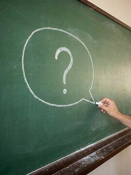 Hand question mark in chalk on green chalkboard blackboard