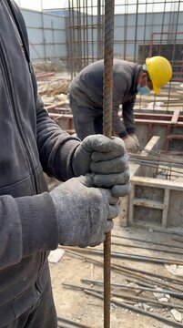 Construction worker gripping rusted rebar at site steel