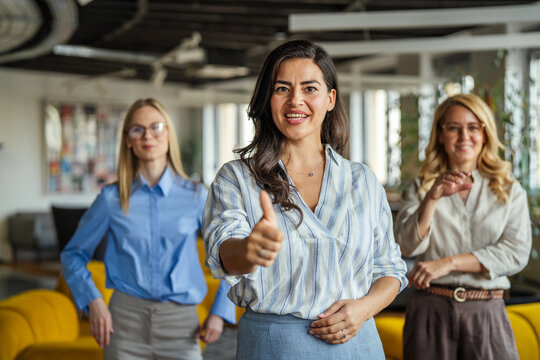 Successful businesswomen showing thumbs up in modern office