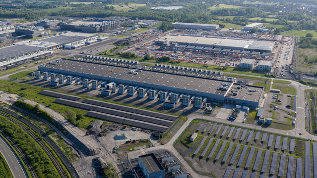 Aerial view of the Google data center complex featuring large industrial buildings, rooftop cooling units, and extensive solar panel arrays in Saint-Ghislain, Region wallonne, Belgium.