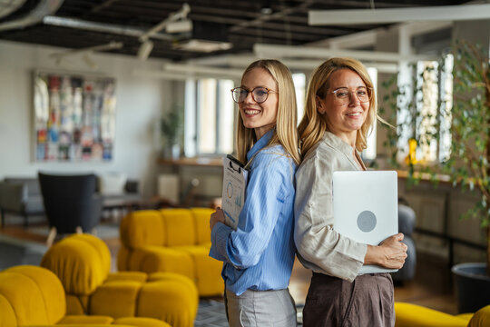 Professional businesswomen coworkers standing back to back in modern office