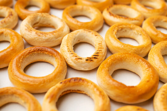 Fresh bagels form close-up food composition on pale background. Ring pastries with golden crust and baked texture suit bakery promotion, snack campaigns, breakfast menus and commercial food design.