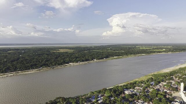 Wide drone footage of the Gorai River in Kushtia, showing a broad waterway, green riverside landscape, distant fields, blue sky, and large clouds.