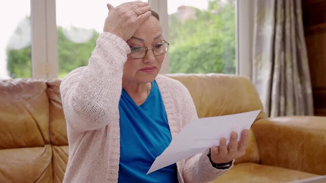 Older woman reads letters at home and shows different emotions