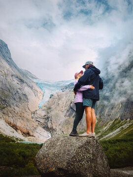 Couple embracing in mountains travel together romantic holidays trip in Norway, family relationship man and woman hiking at Briksdalsbreen glacier adventure lifestyle outdoors, love bonding moments