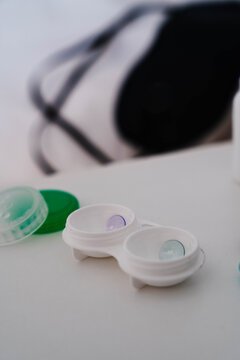 Orthokeratology night lenses in a contact lens case with a sleep mask in the background. Overnight corneal reshaping supports myopia control and vision correction