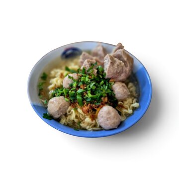 Indonesian meatballs bakso noodle soup topped with fresh celery and fried shallots on white background