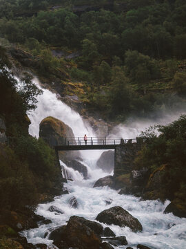 Woman standing on bridge enjoying waterfall view travel solo in Norway tourist hiking in mountains active summer vacations healthy lifestyle tour explore Stryn, freedom harmony with nature