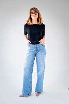 Full lenght studio portrait of a blond haired mature woman in casual clothes against isolated background