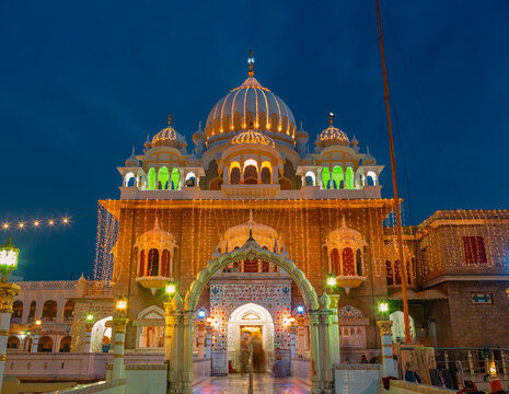 View of the illuminated Gurudwara Sri Panja Sahib at night, featuring its golden dome, intricate architectural details, and decorative string lights in Hassan Abdal, Punjab, Pakistan.
