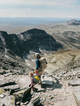 Father and daughter climbing Rondeslottet mountain in Norway family vacations travel together outdoor, parent and child hiking with backpacks gear, explore Rondane trails in summer