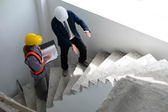 Construction engineer inspecting an unfinished concrete staircase with a site supervisor, focusing on structural safety, quality control, project progress, building inspection, construction management