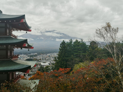 View of Chureito Pagoda overlooking the city of Fujiyoshida with Mount Fuji in the background under a cloudy sky in Fujiyoshida, Yamanashi, Japan.