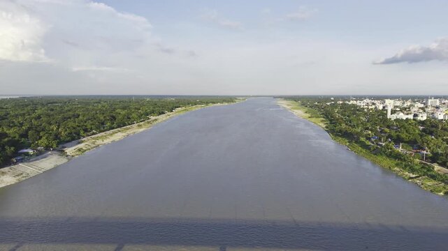 Aerial drone footage slowly moving backward over the Gorai River, initially showing the river and its green banks before Haripur Bridge gradually appears in the frame.