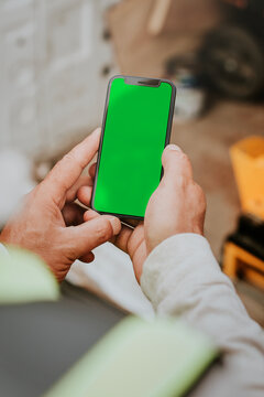 Hands holding smartphone with green screen, suitable as mockup