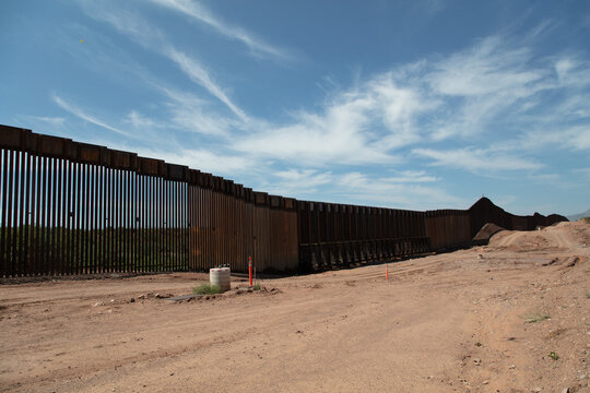 View of the Border Wall stretching across the desert landscape under a clear blue sky in Naco, Arizona, United States.