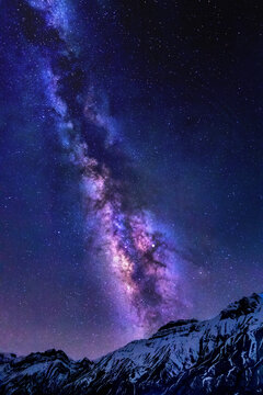 View of the Milky Way galaxy stretching across the night sky above the snow-covered peaks of Spiti Valley in Marango Rangarik, Himachal Pradesh, India.