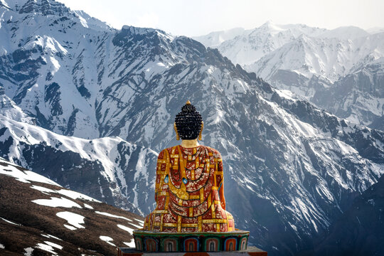 View of a colorful Buddha statue overlooking the snow-capped peaks of the Spiti Valley in the Himalayas, Marango Rangarik, Himachal Pradesh, India.