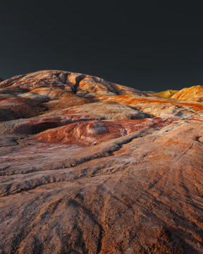 View of the colorful striped sedimentary rock formations of the Candy Cane Mountains under a dramatic dark sky in Azerbaijan.