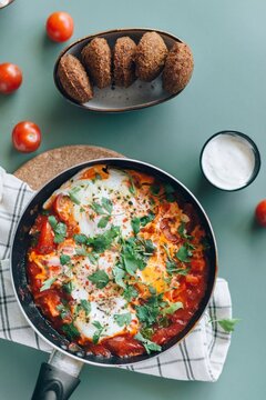 Traditional Middle Eastern breakfast with skillet shakshuka poached eggs, falafel, and tahini sauce
