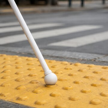White cane tip on tactile paving studs closeup