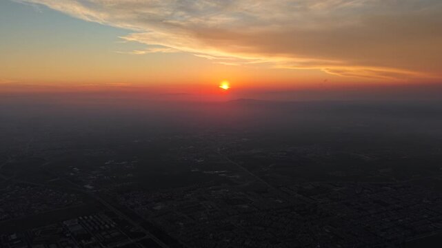 Aerial drone view of an urban landscape in Syria at sunrise. City skyline and residential neighborhoods bathed in morning light. Middle Eastern city view under a golden dawn sky. 