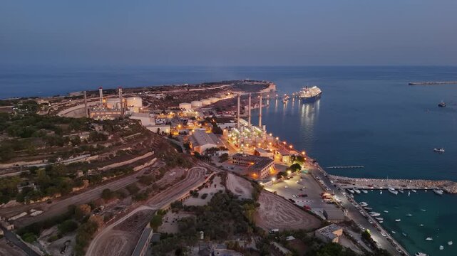 Delimara power plant in Marsaxlokk, Malta, with LNG CCGT infrastructure, illuminated coastal industrial buildings and chimneys beside the Mediterranean Sea at night, aerial