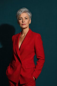 Woman with short silver hair in a red blazer studio portrait