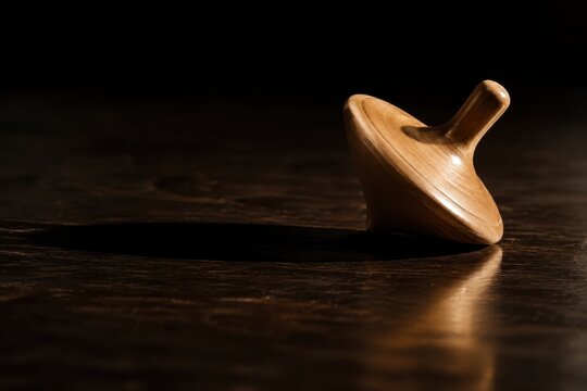 Wooden spinning top slowing to a stop on a dark table
