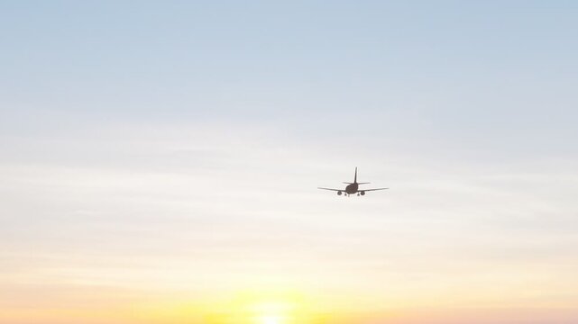 Commercial passenger airplane flying through a warm sunset sky, ideal for aviation, air travel, tourism, transportation, airline, and travel content.