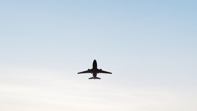 Commercial passenger airplane flying through a warm sunset sky, ideal for aviation, air travel, tourism, transportation, airline, and travel content.
