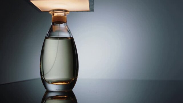 Lowering square panel increasing warm glow on glass bottle on studio tabletop, revealing dip tube