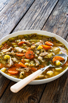 Krupnik - polish barley soup with chicken meat on wooden table
