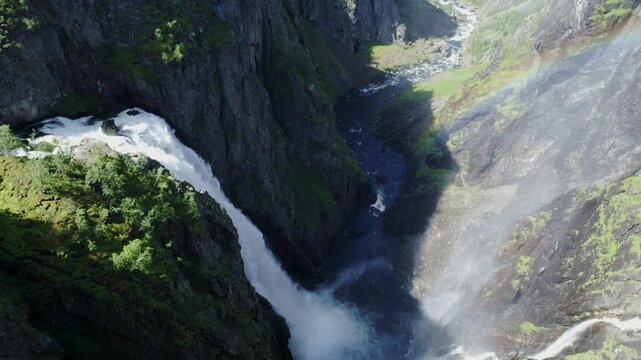Voringfossen plunges through Norway canyon as sunlight creates rainbow in mist