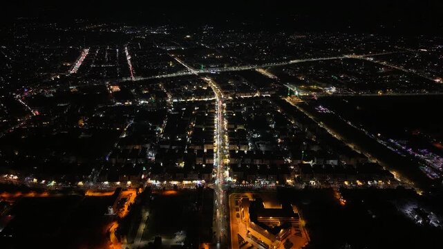 Aerial night view of an urban landscape in Syria featuring glowing city lights and illuminated streets.  Post-war Syrian cityscape and daily life at night.