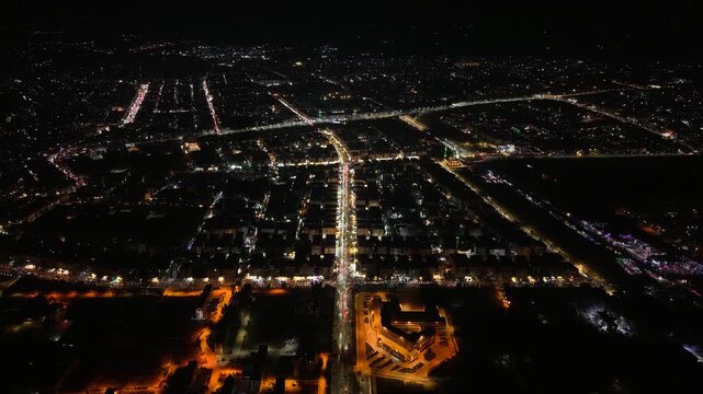 Aerial night view of an urban landscape in Syria featuring glowing city lights and illuminated streets.  Post-war Syrian cityscape and daily life at night.