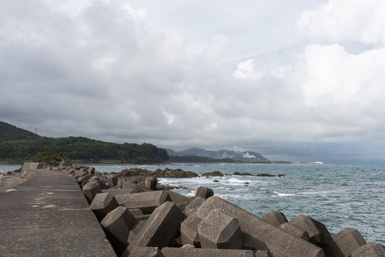 Concrete Tetrapod Wave Breakers on Japanese Coastline with Ocean Waves and Cloudy Sky in Wakayama Copy Space Background