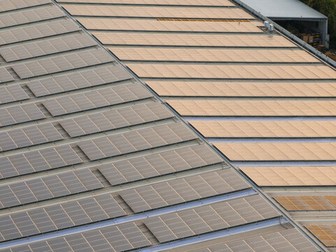 Aerial view of a large industrial roof covered with rows of solar panels in Fermo, Marche, Italy.
