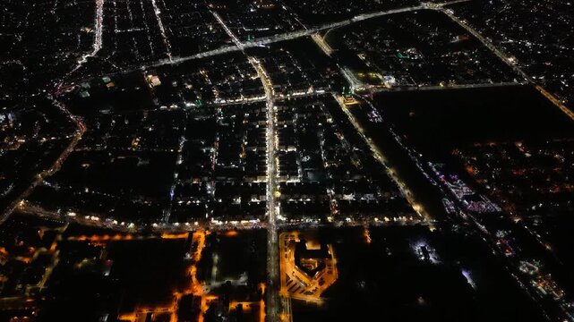 Aerial night view of an urban landscape in Syria featuring glowing city lights and illuminated streets.  Post-war Syrian cityscape and daily life at night.