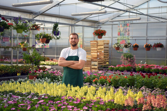 happy worker growing flowers in a greenhouse of a flower shop