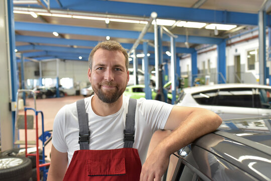 Portrait of a smiling car mechanic in a professional workshop - closeup photo