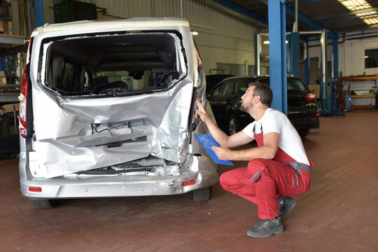 Car mechanic examines accident vehicle in a workshop for repair