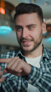Cheerful gadget addicted Caucasian man with mobile phone surprised happy client amazed with online order pointing in screen in shopping mall carefree business male businessman with smartphone indoors